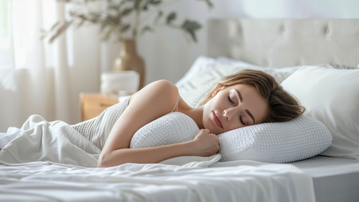 Femme dormant paisiblement sur le côté avec un oreiller cervical ergonomique maintenant un alignement optimal de la colonne vertébrale