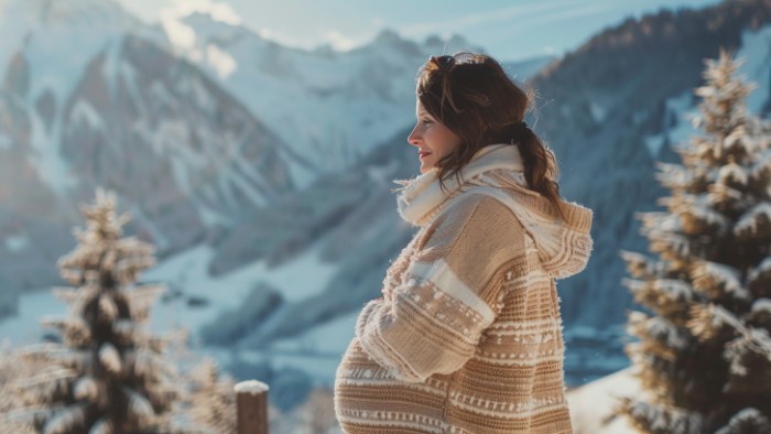 Femme enceinte profitant sereinement de la montagne en station de ski avec paysage enneigé