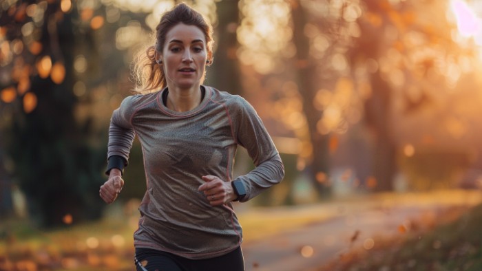 Femme coureuse de 30 ans en pleine course à pied matinale montrant une vitesse moyenne régulière sur un parcours en parc