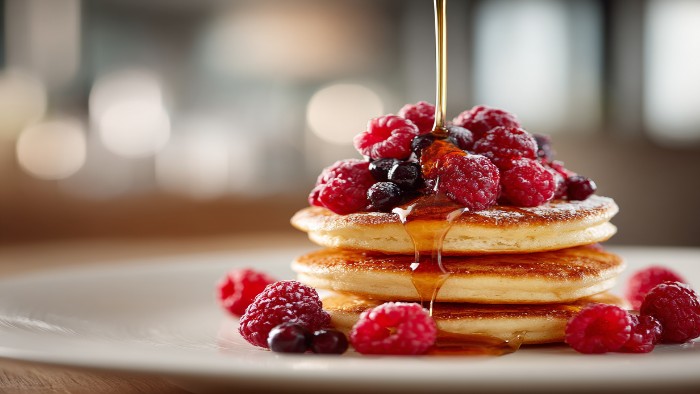 Pancakes protéinés moelleux recouverts de fruits rouges et de sirop d'érable, prêts à être dégustés.
